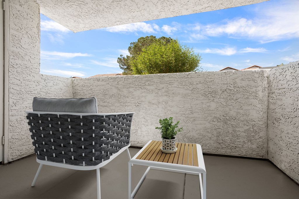 a small balcony with a chair and a small table with a plant on it